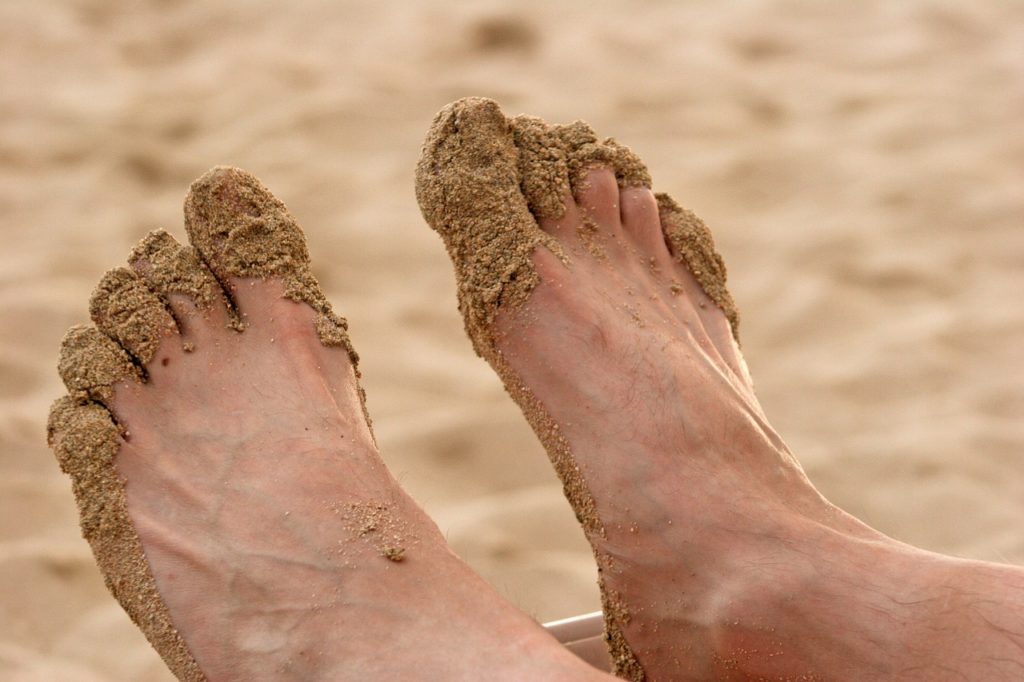 мужские стопы и ногти в песке
